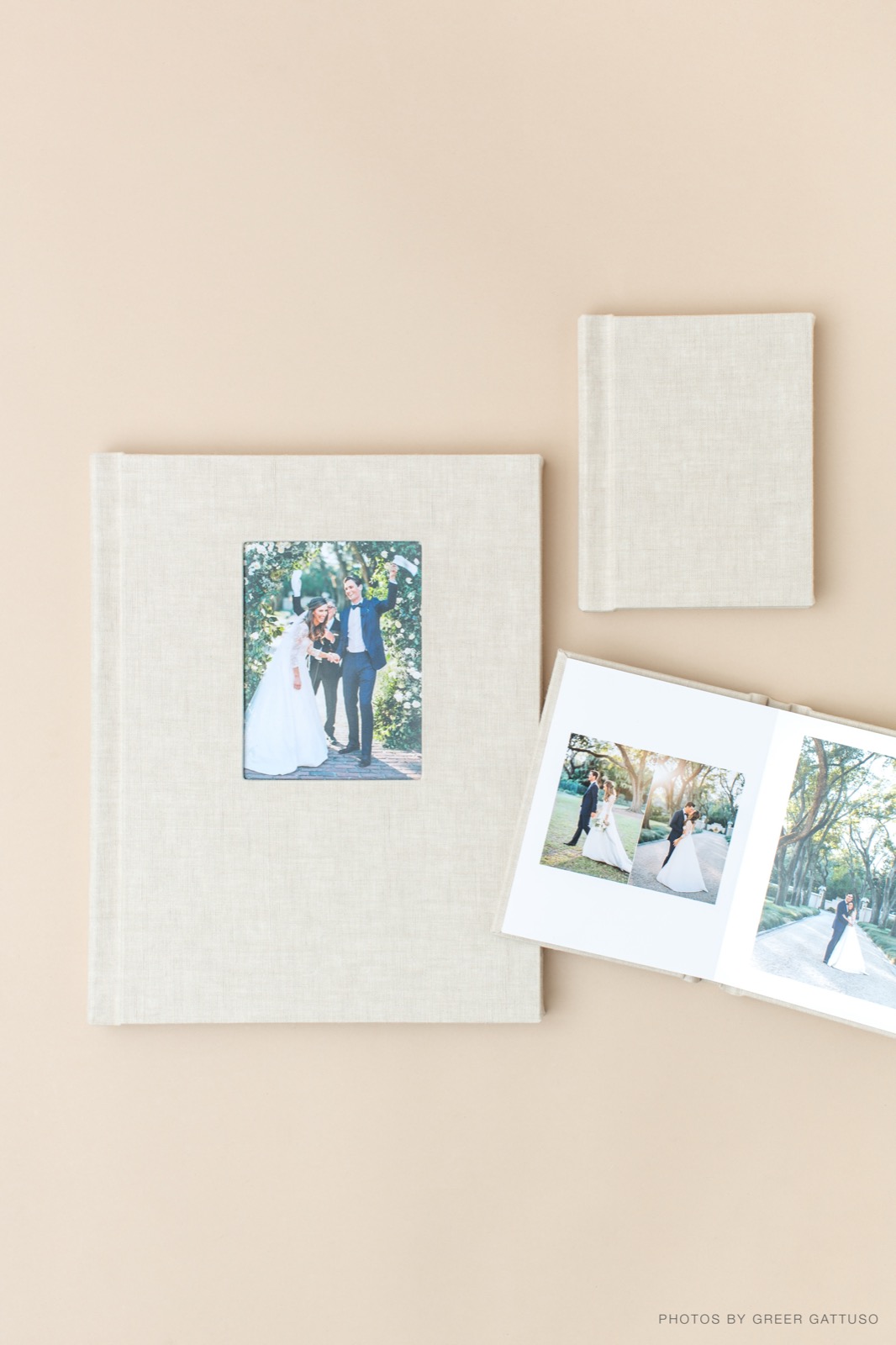 Linen-covered wedding albums with a photo cover window, one open to a spread of couple portraits