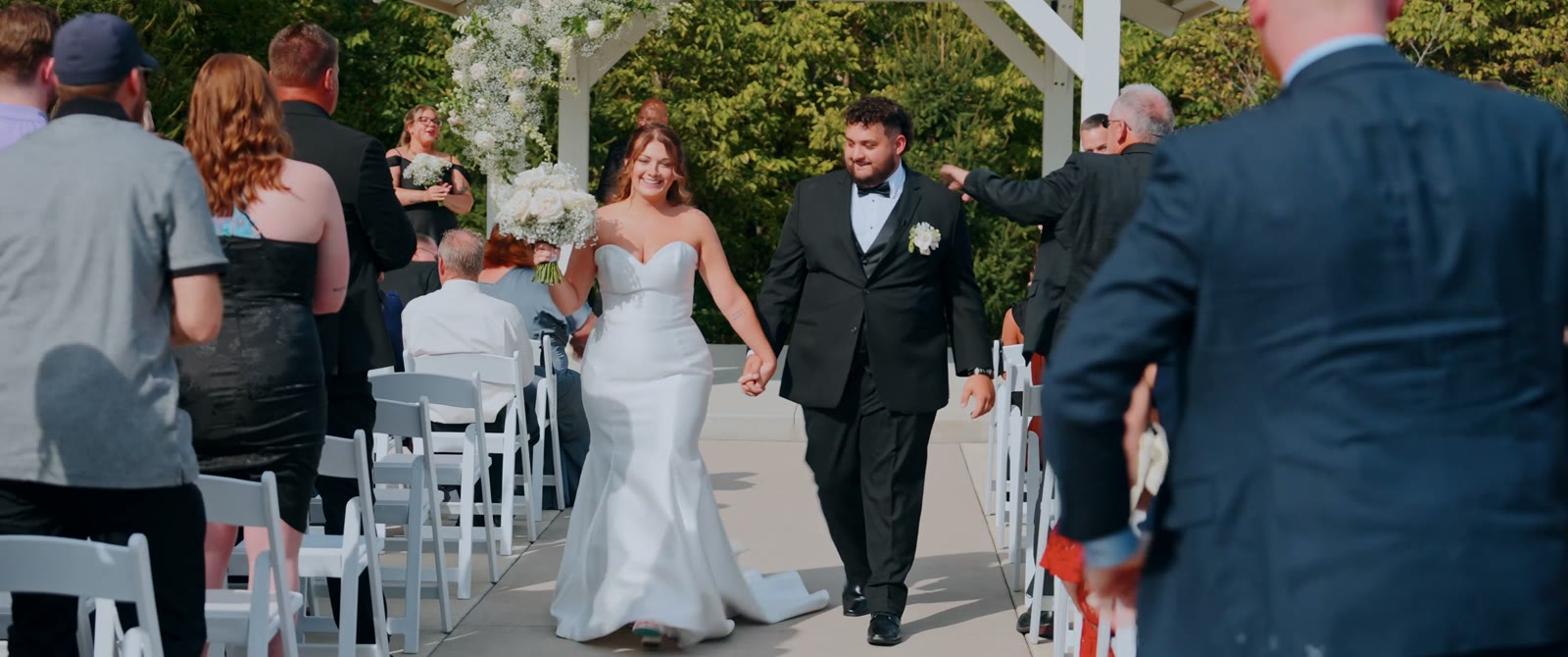 Jacey and Ryan walk back down the outdoor aisle hand in hand as guests cheer.