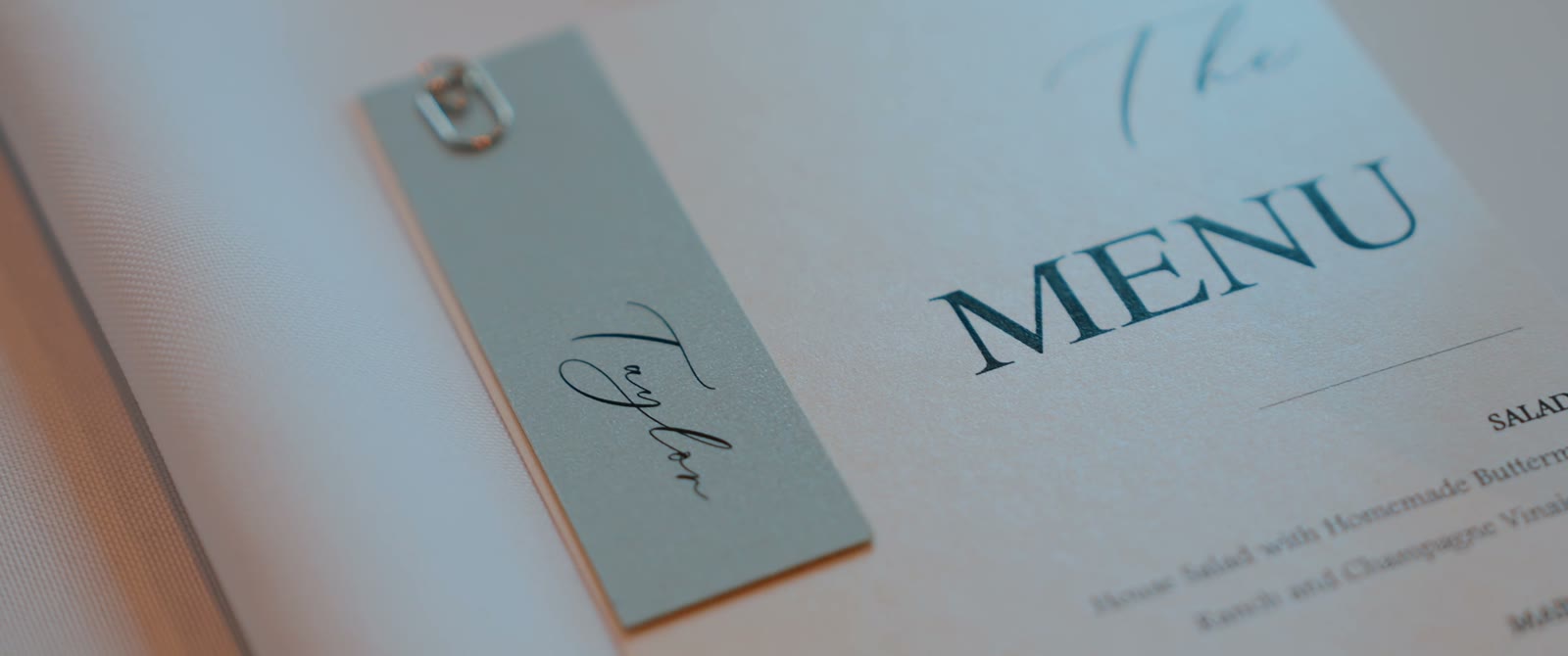 Detail of a reception menu card with a handwritten name tag clipped beside it.