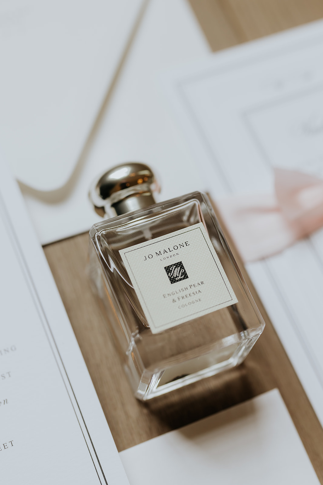 Jo Malone English Pear and Freesia cologne bottle resting on Brooklyn and Jared's wedding invitation suite