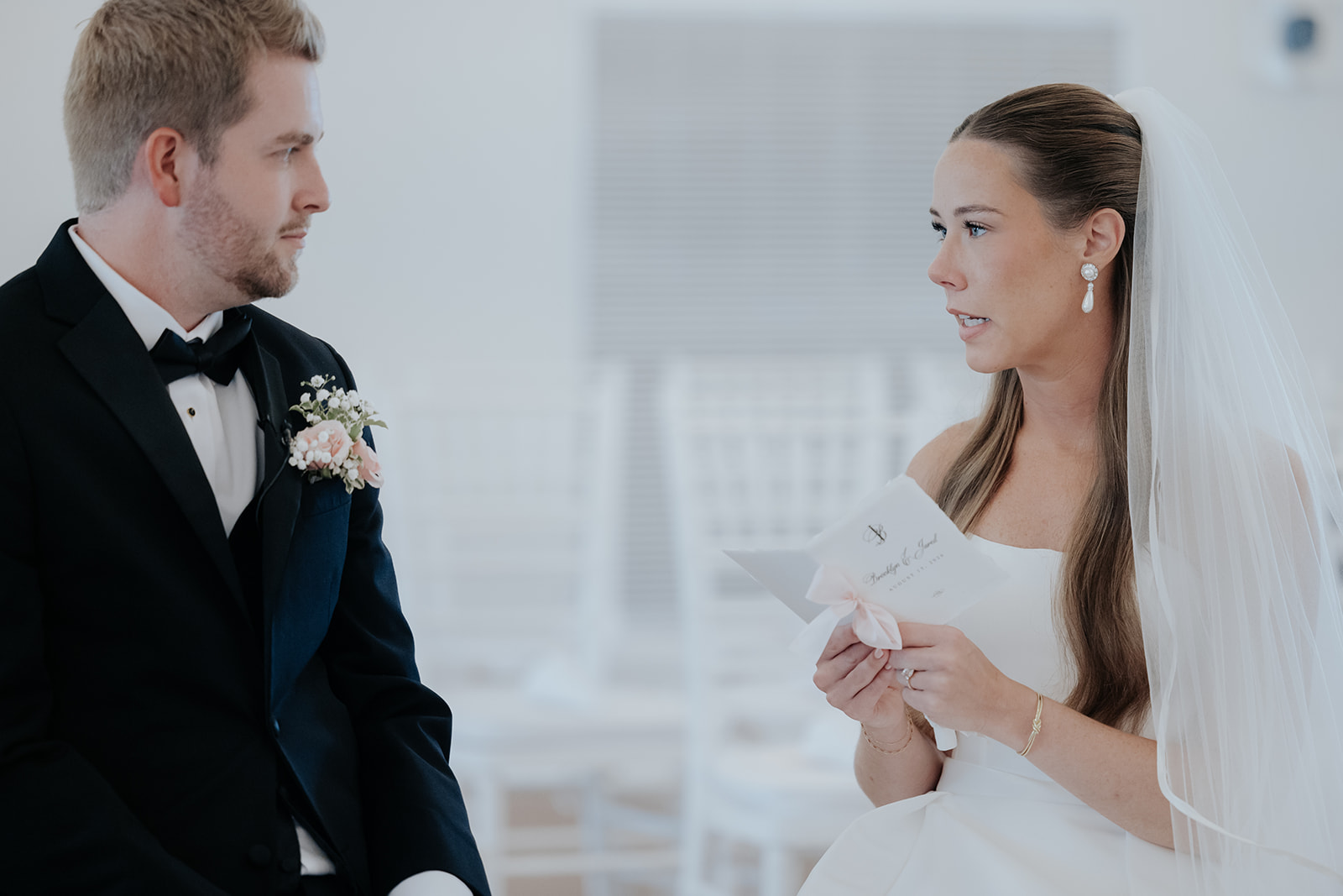 The bride reads a handwritten letter to the groom as he listens closely during a private moment