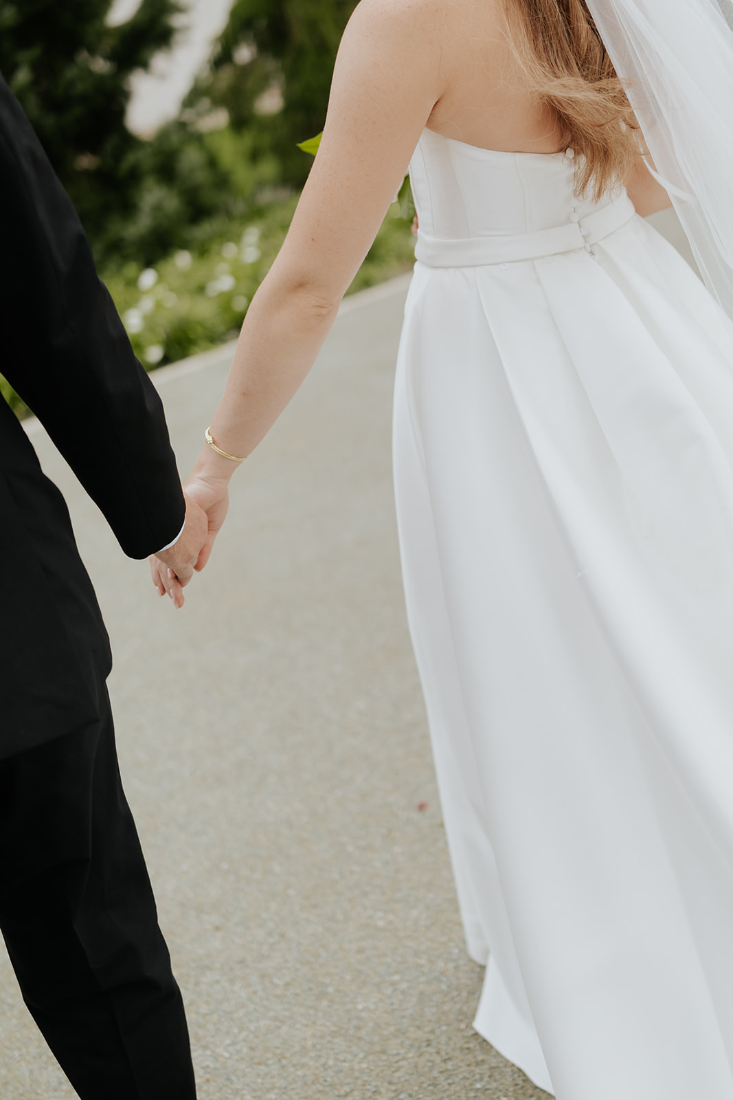 Close-up of Brooklyn and Jared holding hands as they walk down a garden path
