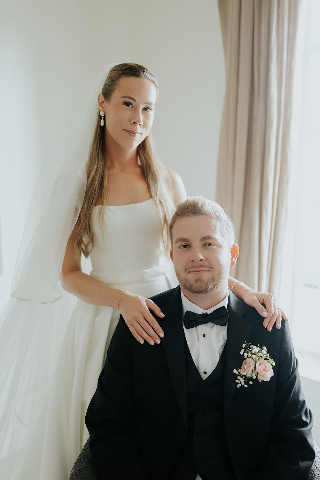 Brooklyn stands with her hands on Jared's shoulders as he sits for a classic wedding portrait