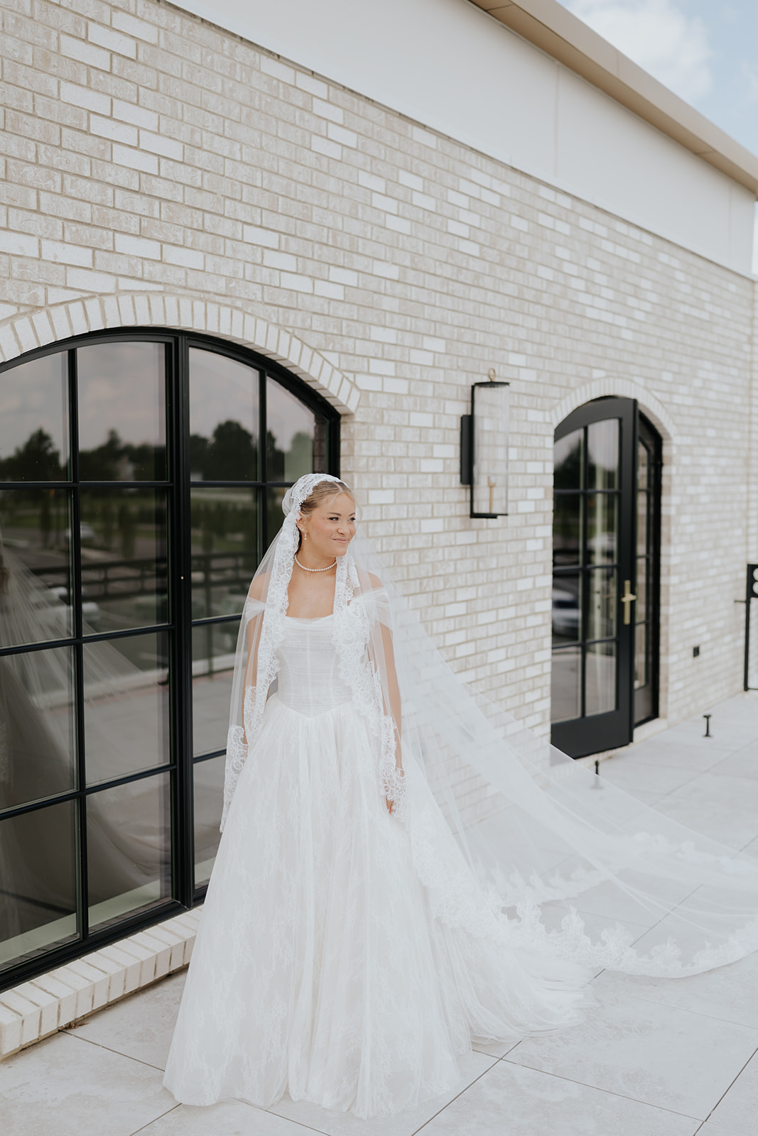 The bride stands on the rooftop terrace at Westwood Vowery & Estate, her long cathedral veil trailing.