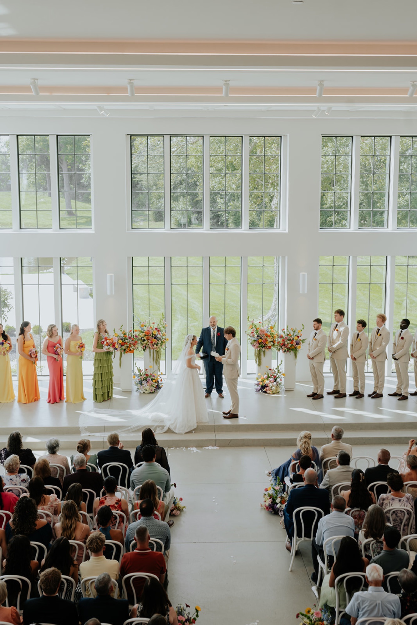 Cami and Trey's ceremony at Westwood Vowery & Estate, bridesmaids in bright colors and groomsmen in tan.
