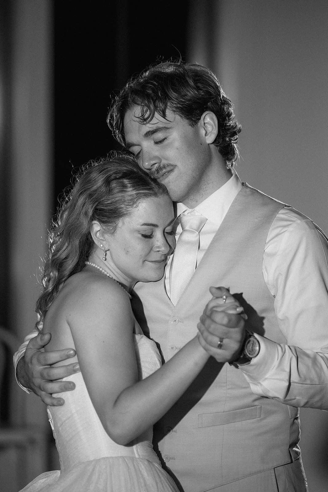 Black and white photo of Cami and Trey dancing cheek to cheek with their eyes closed.