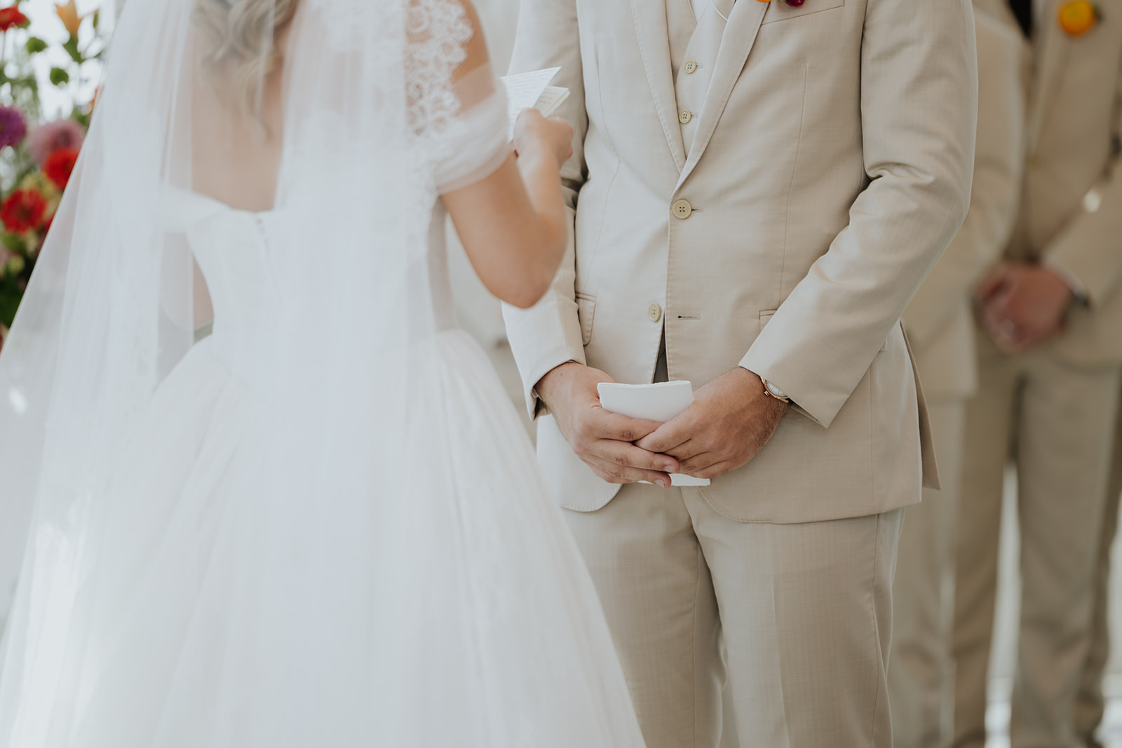 The bride reads her handwritten vows while the groom holds his own folded vows.