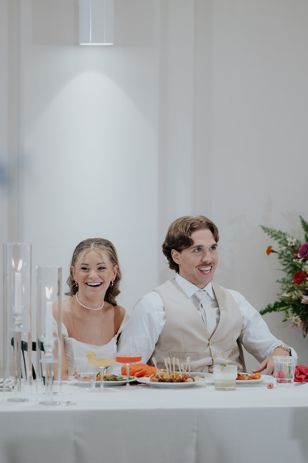 Cami and Trey laugh together at their reception table during the toasts.
