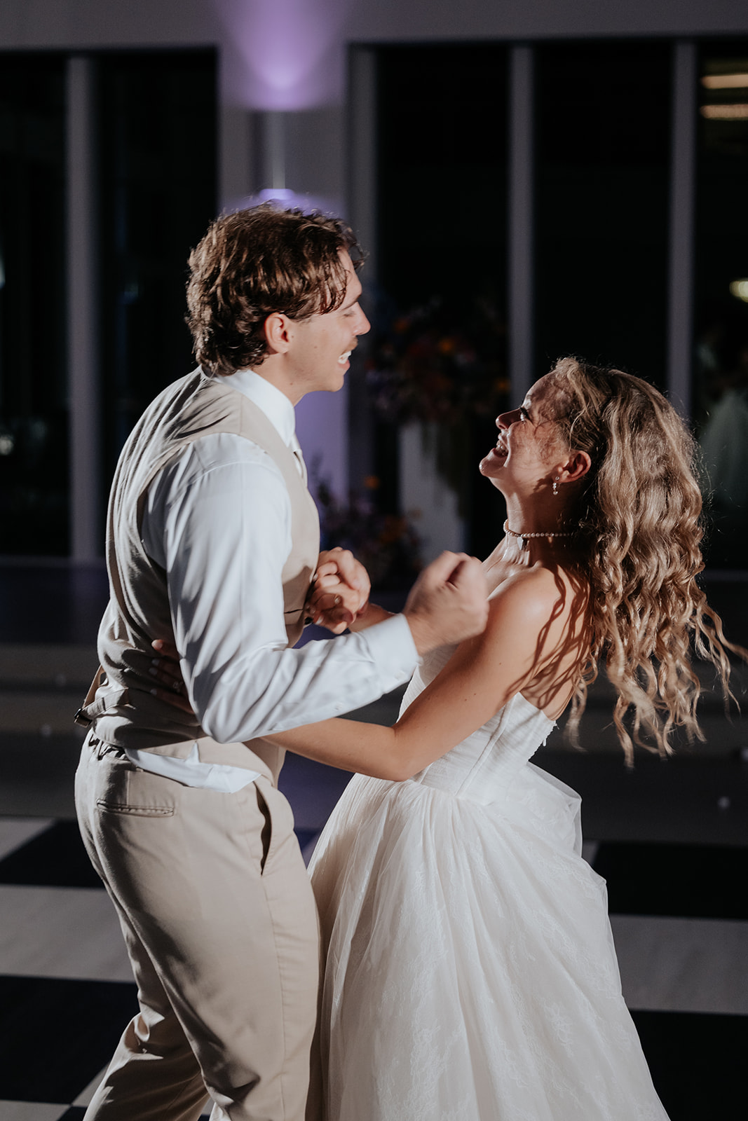 Cami and Trey laugh and dance together on the reception dance floor.