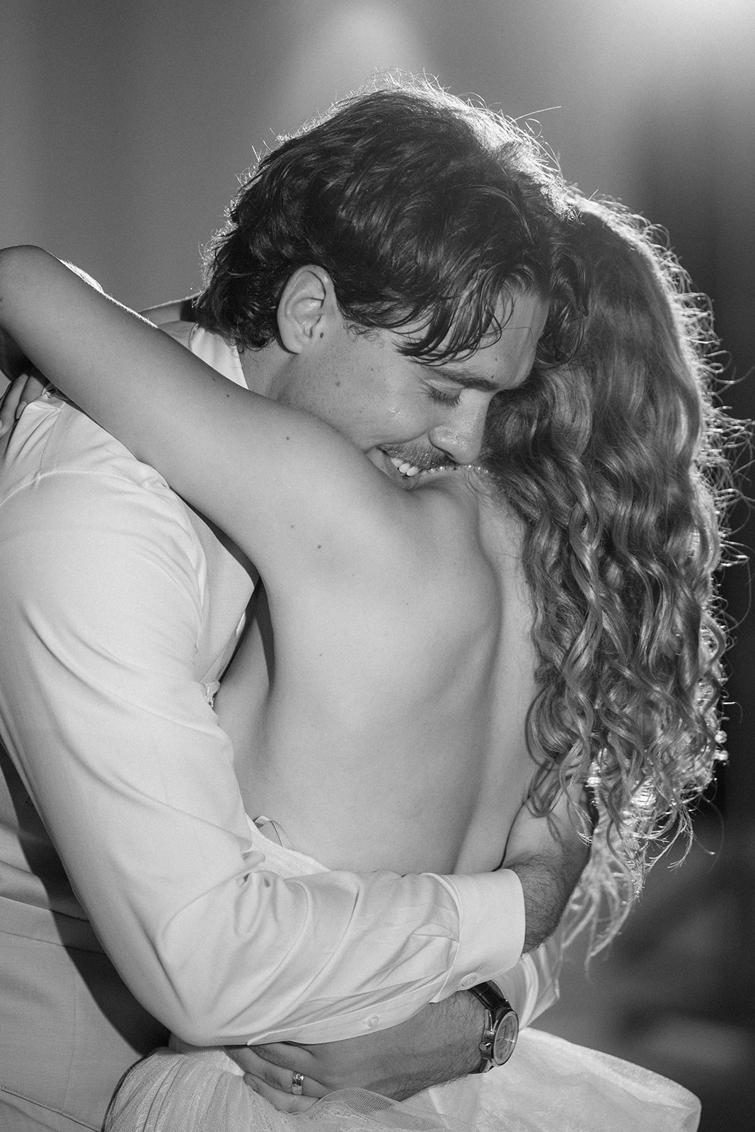 Black and white photo of Cami and Trey embracing tightly on the dance floor, the groom smiling.