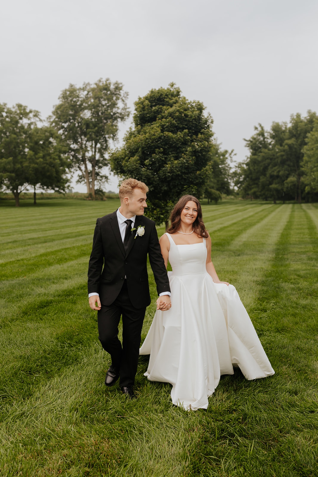 Cody and Kristen walk hand in hand across the freshly mowed lawn at The Sixpence