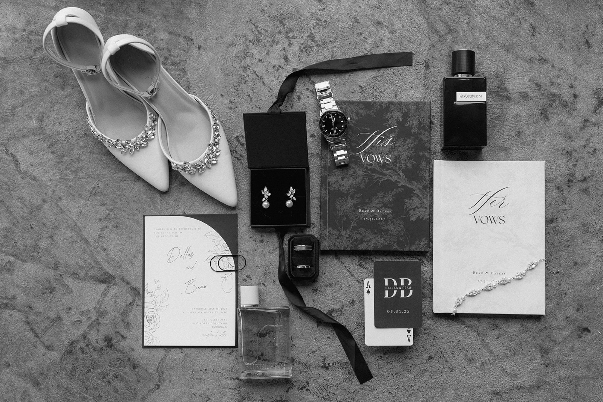 Black and white flat lay of bridal shoes, vow books, watch, earrings, cologne and Dallas and Beau's invitation