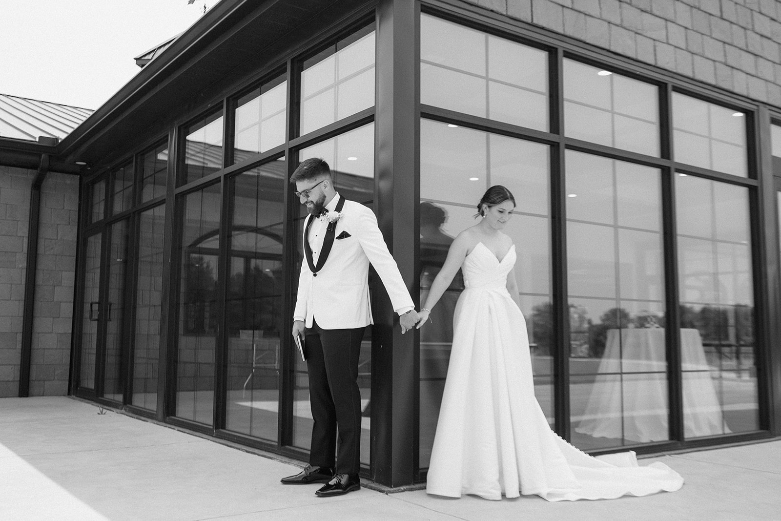Black and white photo of Dallas and Beau holding hands around a corner before seeing each other at The Clubhouse