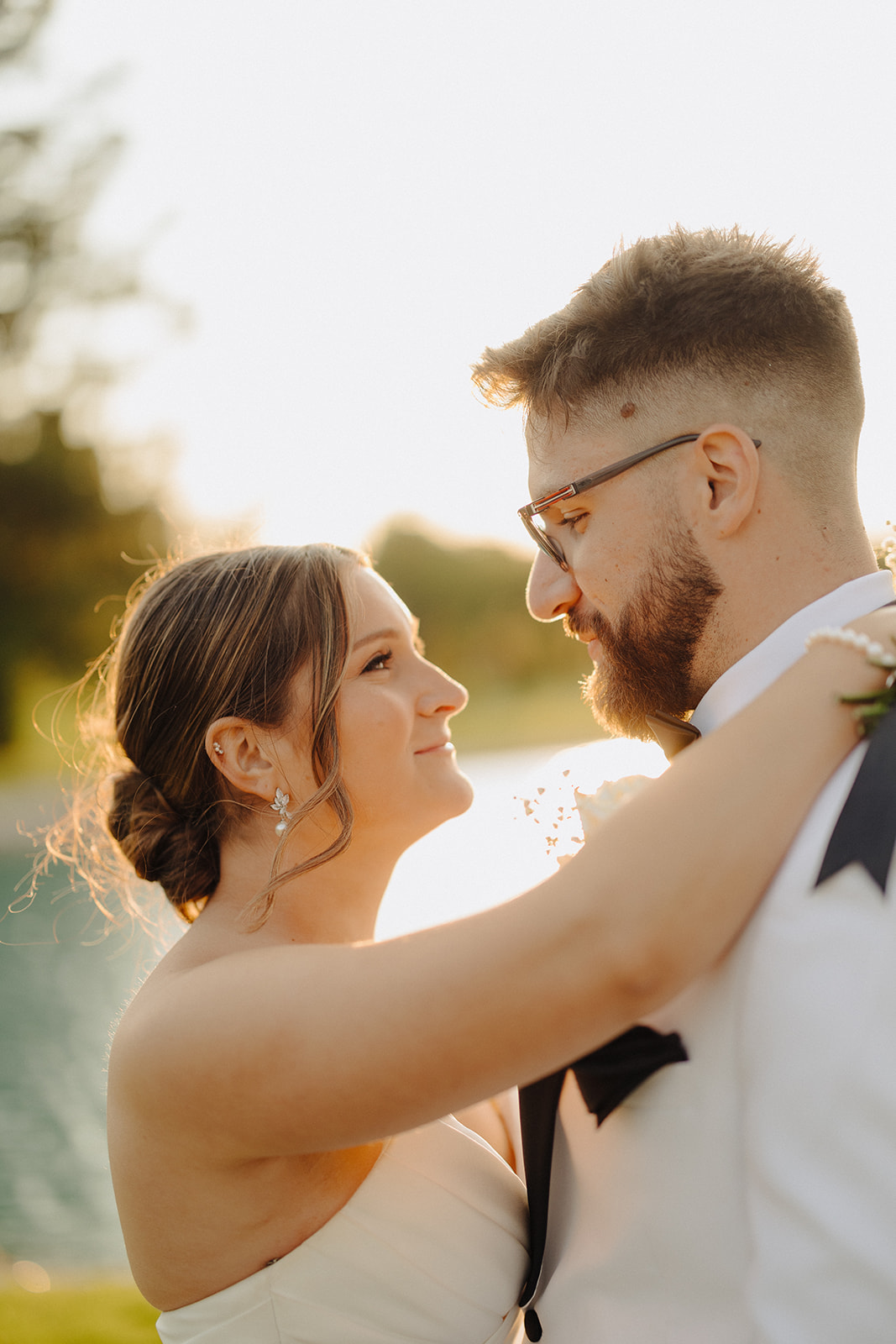 Dallas and Beau gaze at each other and smile in warm golden hour light beside the water.