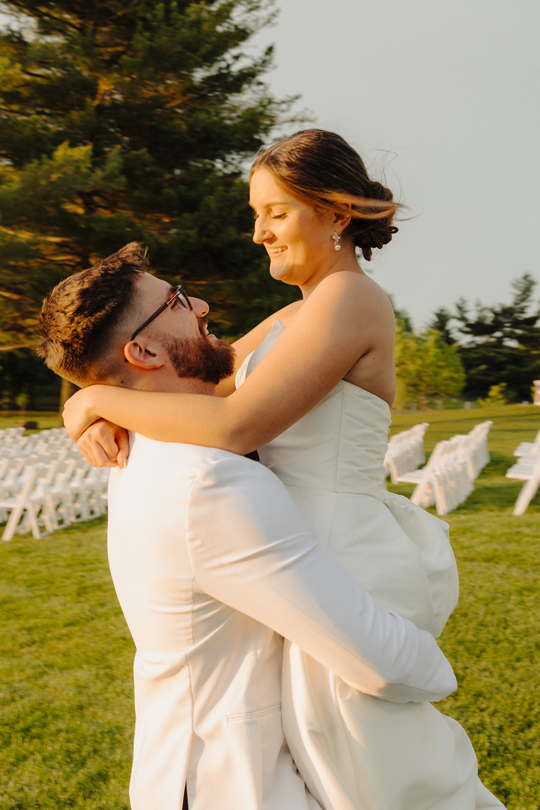 Beau lifts Dallas into the air as she laughs on the lawn beside rows of white ceremony chairs.