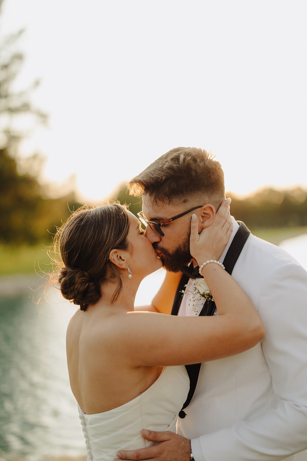 Dallas holds Beau's face as they kiss at sunset with the lake glowing behind them.