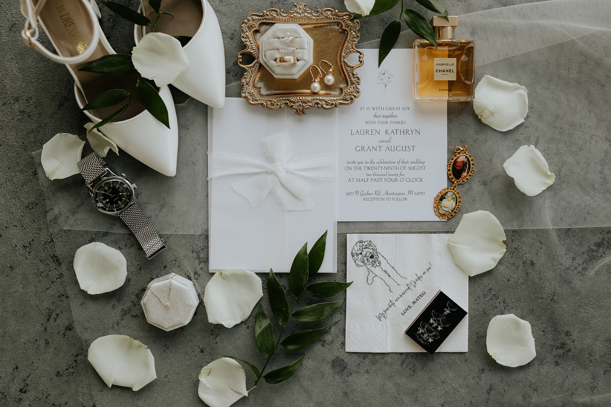 Lauren and Grant's invitation suite styled with rings, pearl earrings, perfume, a watch and white heels