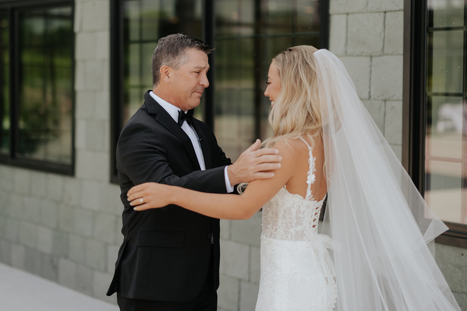 The bride's father turns and sees her in her gown and veil for the first time