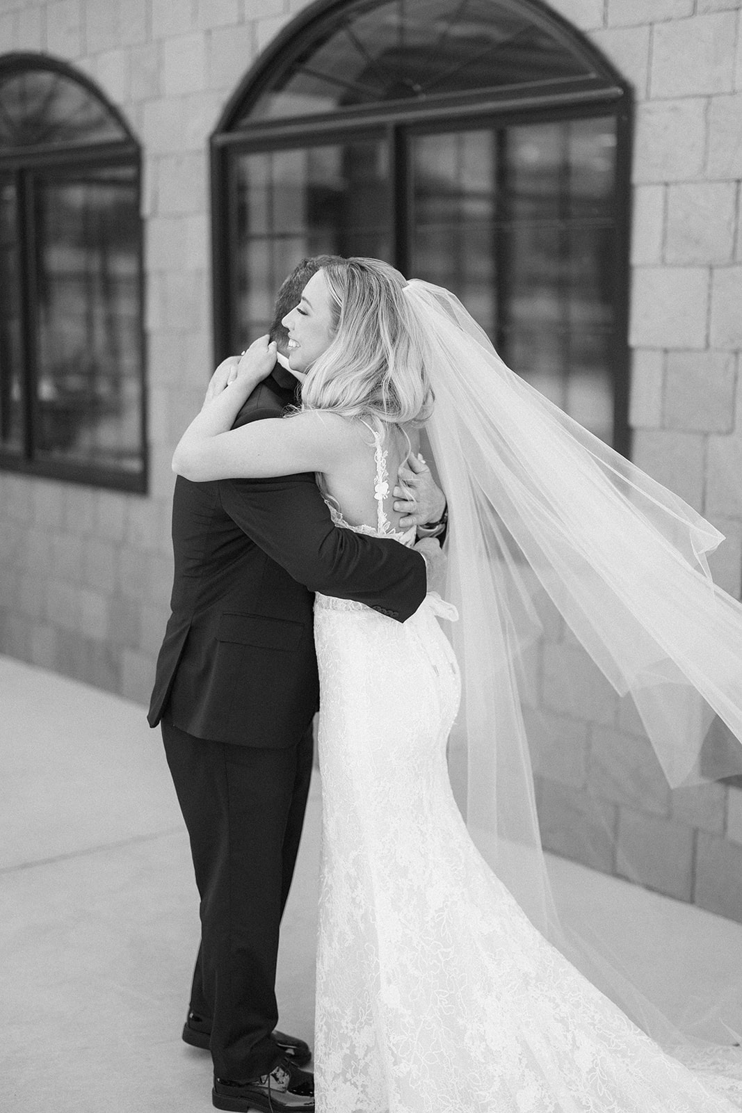 Black and white photo of the bride hugging her father tightly during their first look