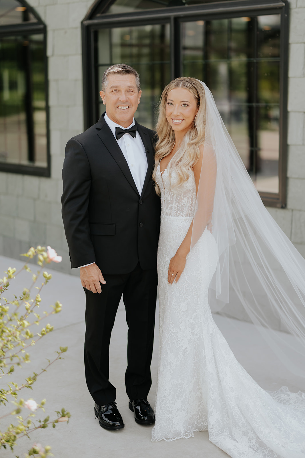 The bride and her father smile together outside the stone venue before the ceremony