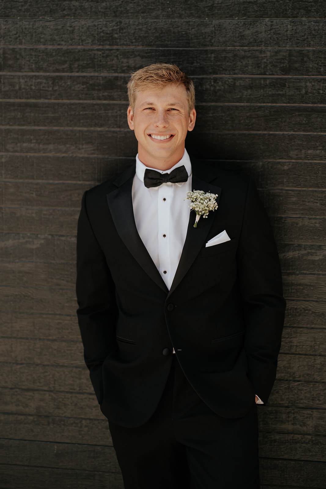 Close portrait of the groom smiling in his black tuxedo, bow tie and white pocket square