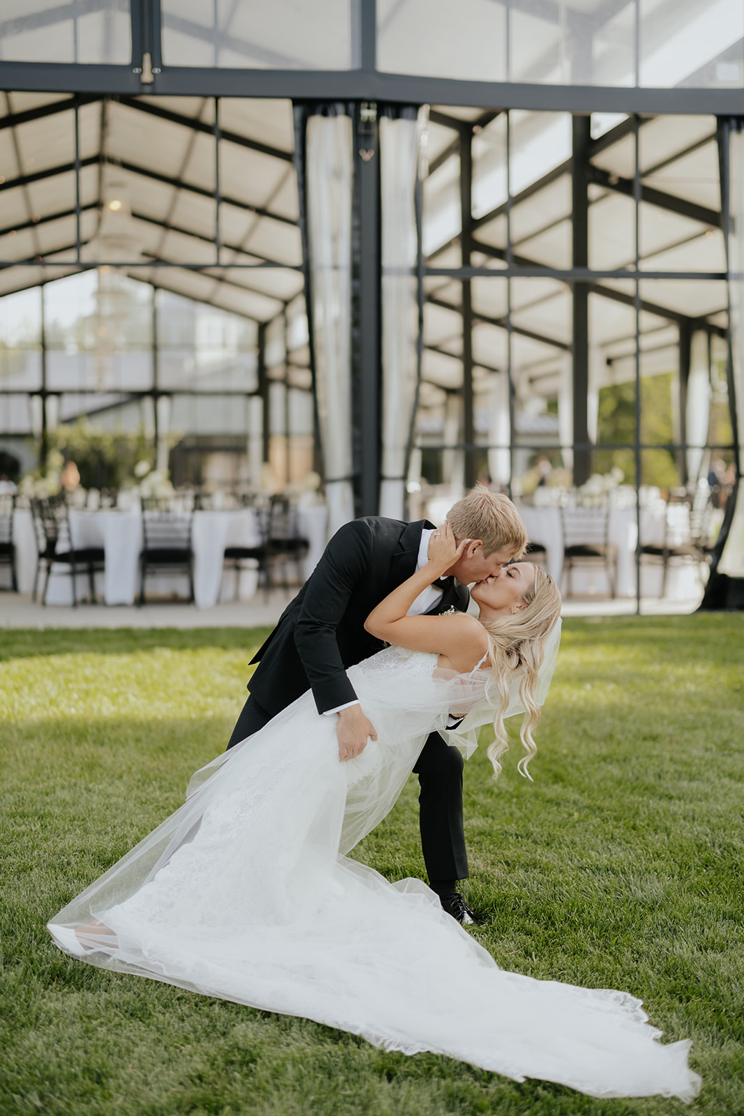 Grant dips Lauren for a kiss on the lawn outside the glass pavilion at The Clubhouse