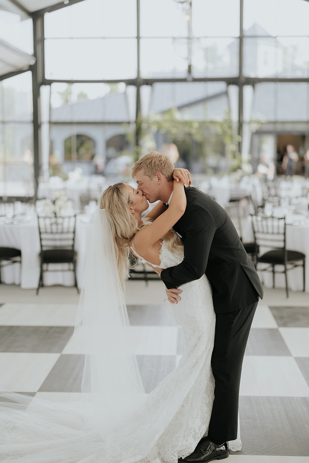 Lauren and Grant kiss on the checkered floor of the empty reception pavilion
