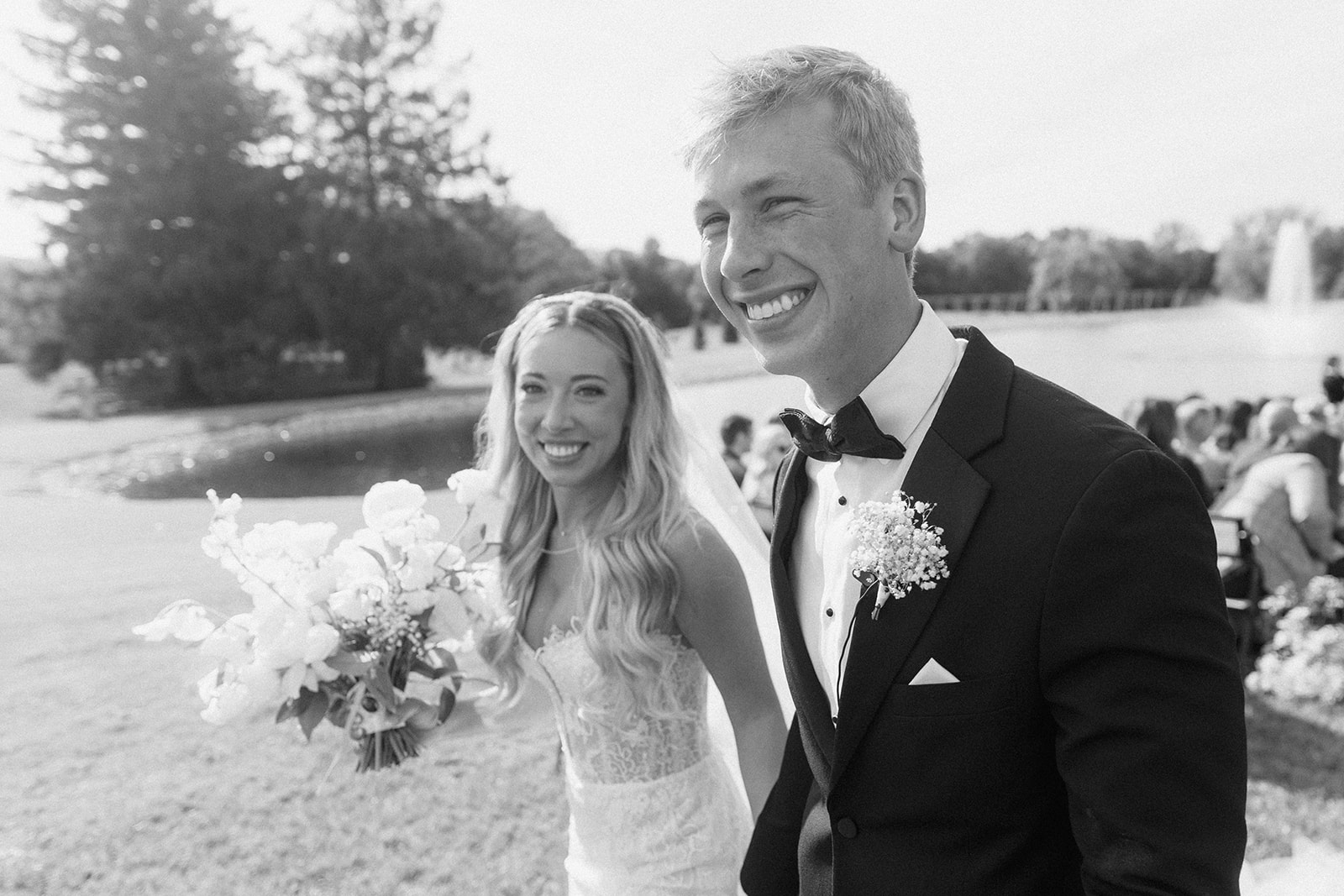Black and white photo of Lauren and Grant beaming as they walk back up the aisle
