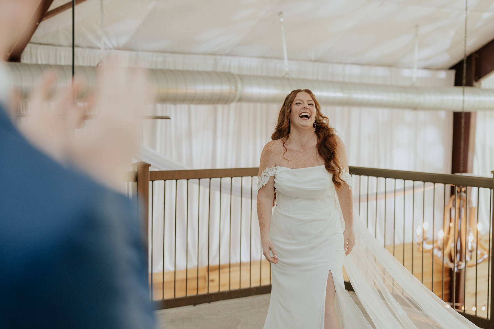 The bride laughs as she walks out in her gown and veil for a first look
