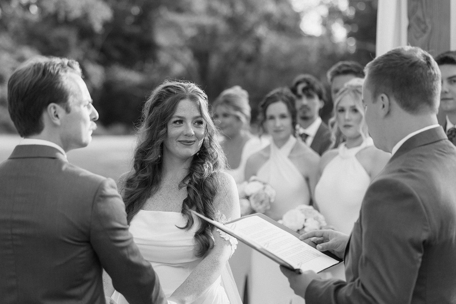 Black and white of Maci and Matt facing each other as the officiant reads during the ceremony