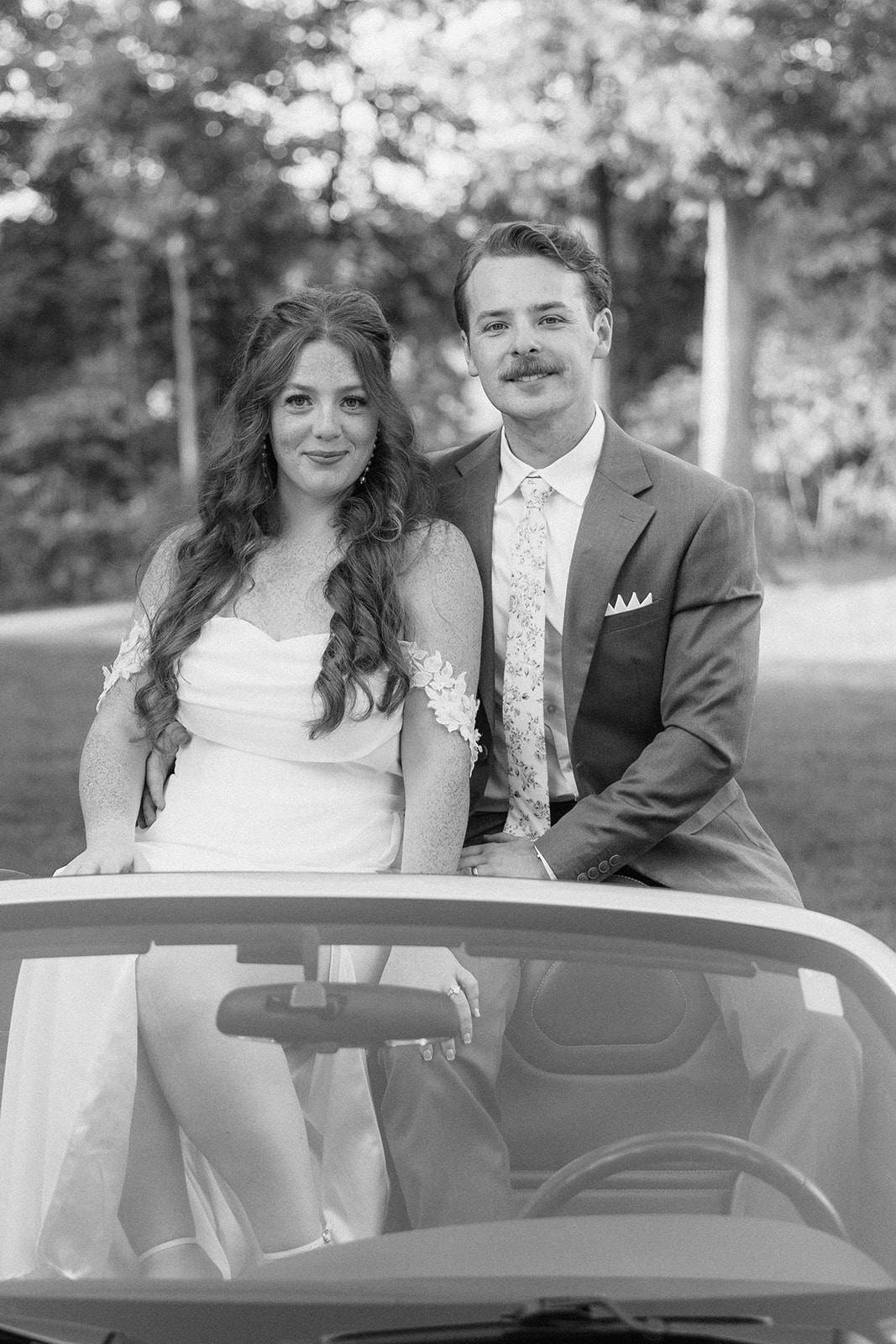 Black and white of Maci and Matt sitting on the back of a convertible car