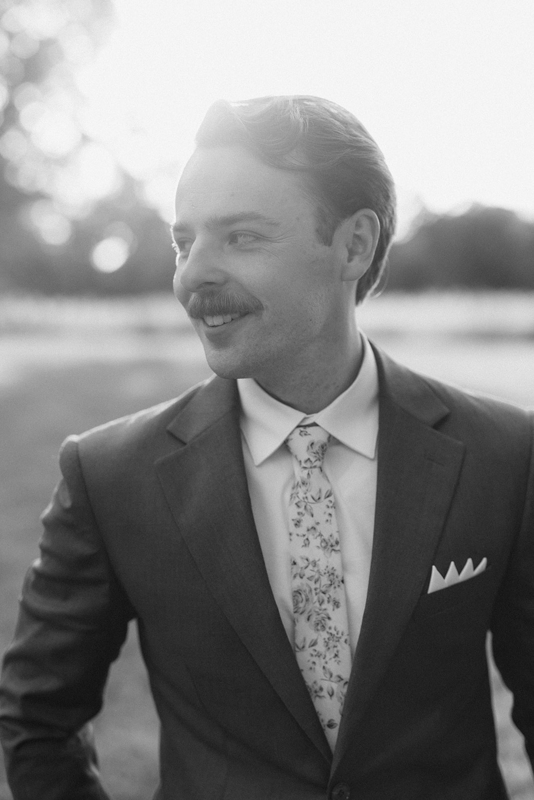 Black and white portrait of the groom smiling in the evening sun