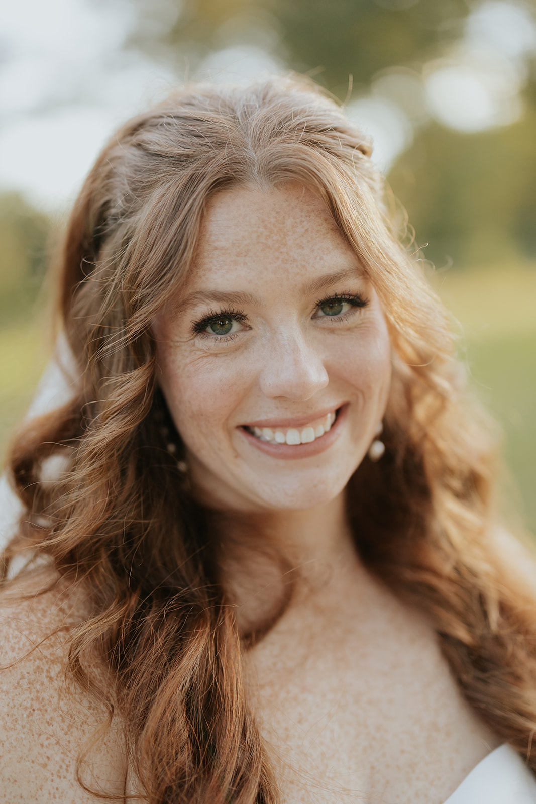 Close-up of the bride smiling in warm golden light with her red hair over her shoulder