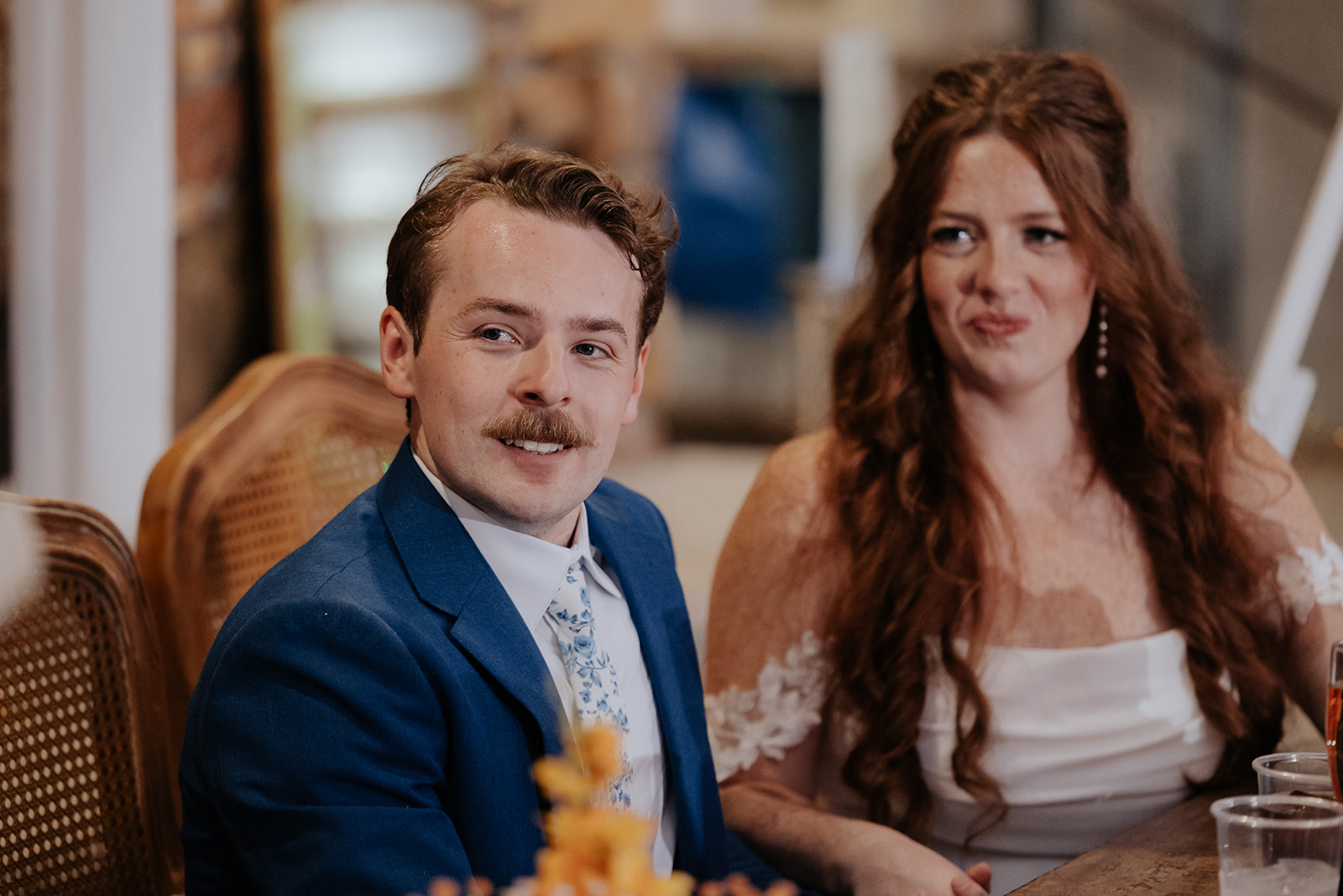 Maci and Matt react to a toast while seated together at the reception
