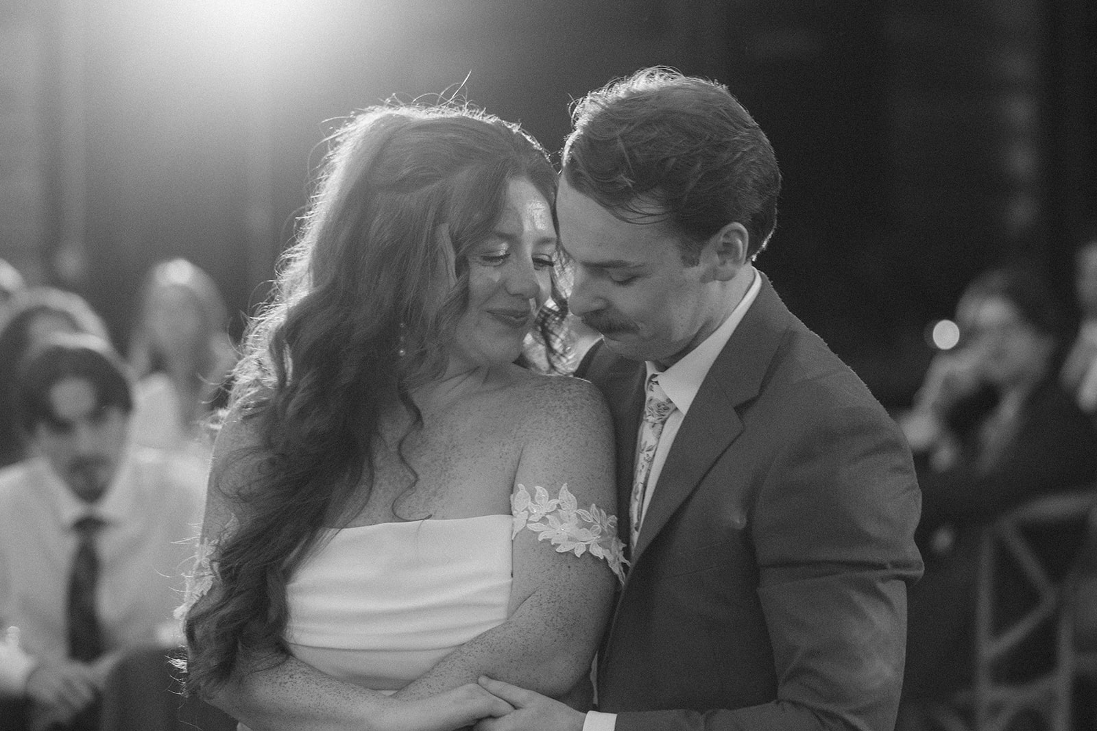 Black and white of Maci and Matt slow dancing as guests watch