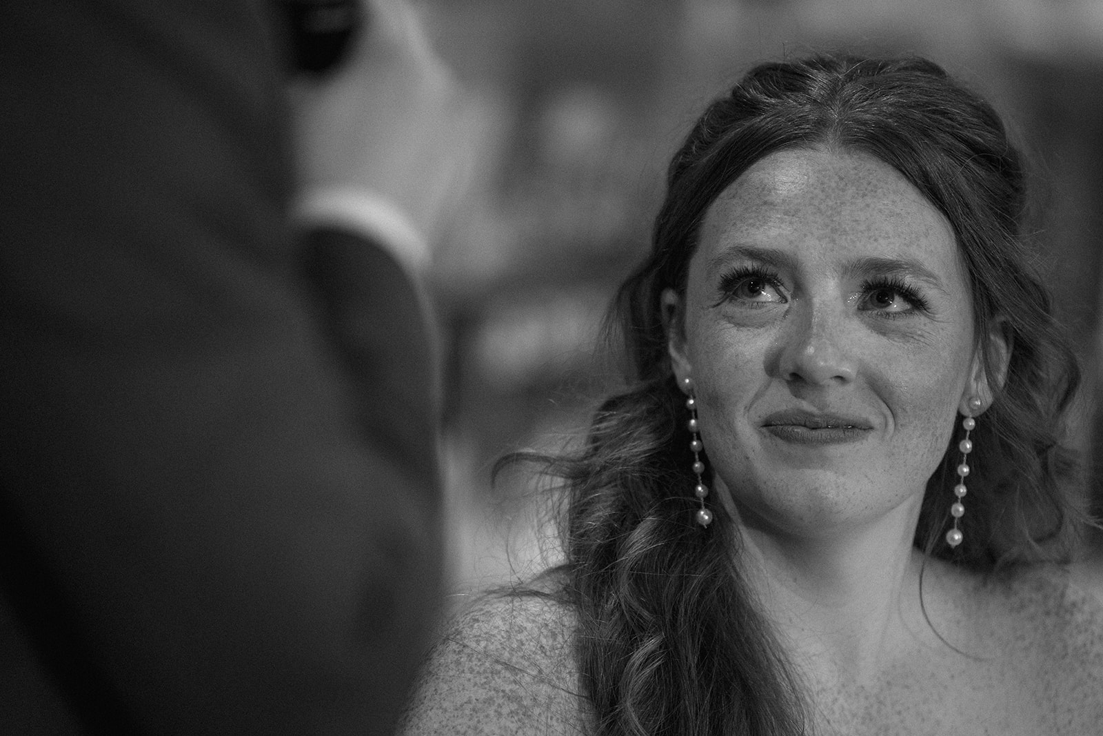 Black and white of the bride listening with teary eyes during a toast