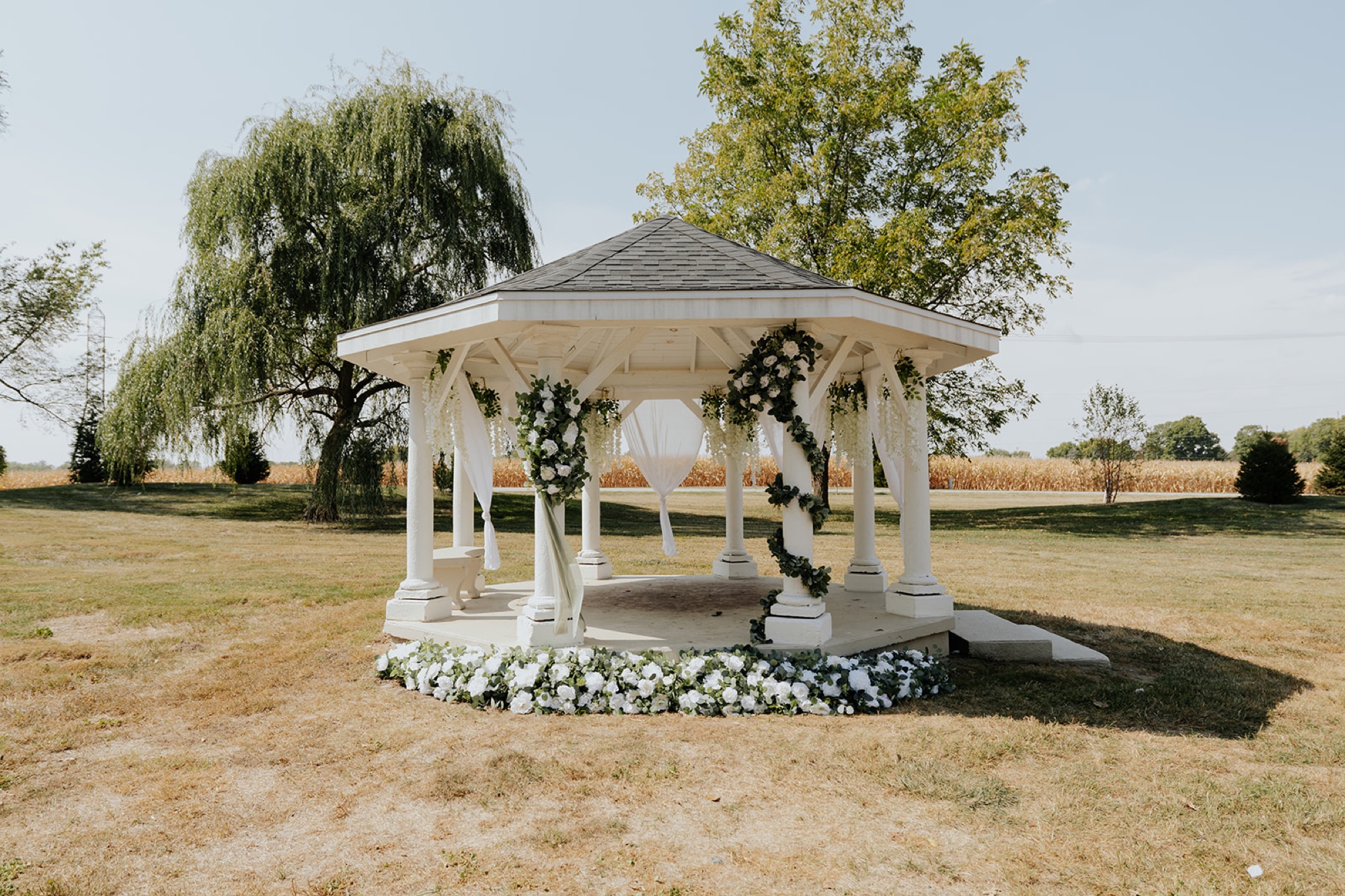 The white gazebo ceremony site at The Venue at Brookstone, framed with greenery and white flowers