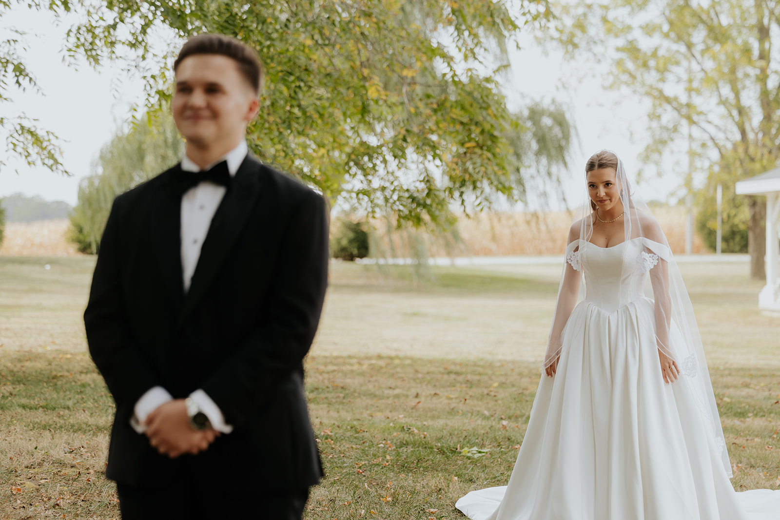 The groom waits with his back turned as the bride walks toward him for their first look