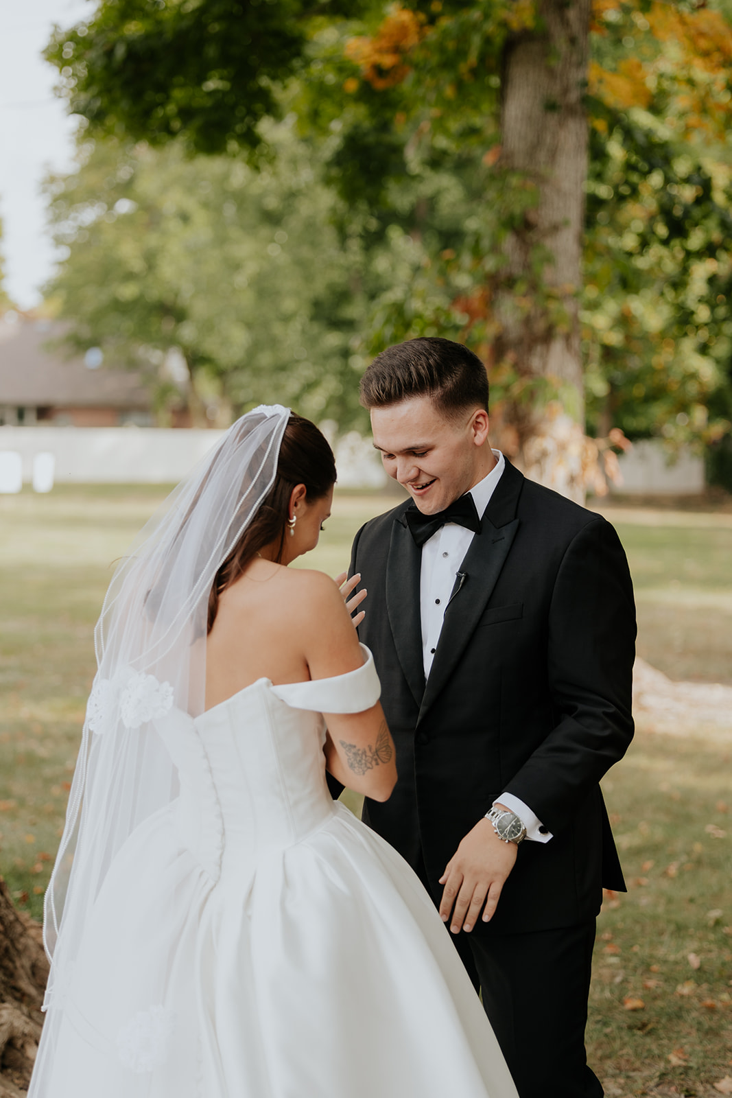 The groom grins as the bride rests her hand on his chest during their first look