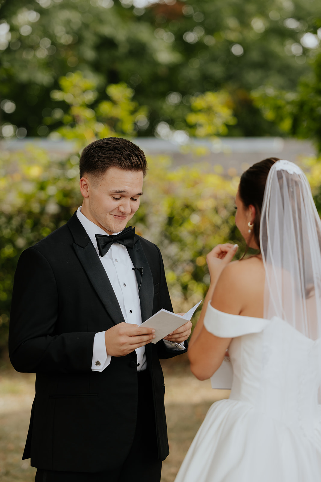 The groom reads private vows from a card as the bride wipes away a tear