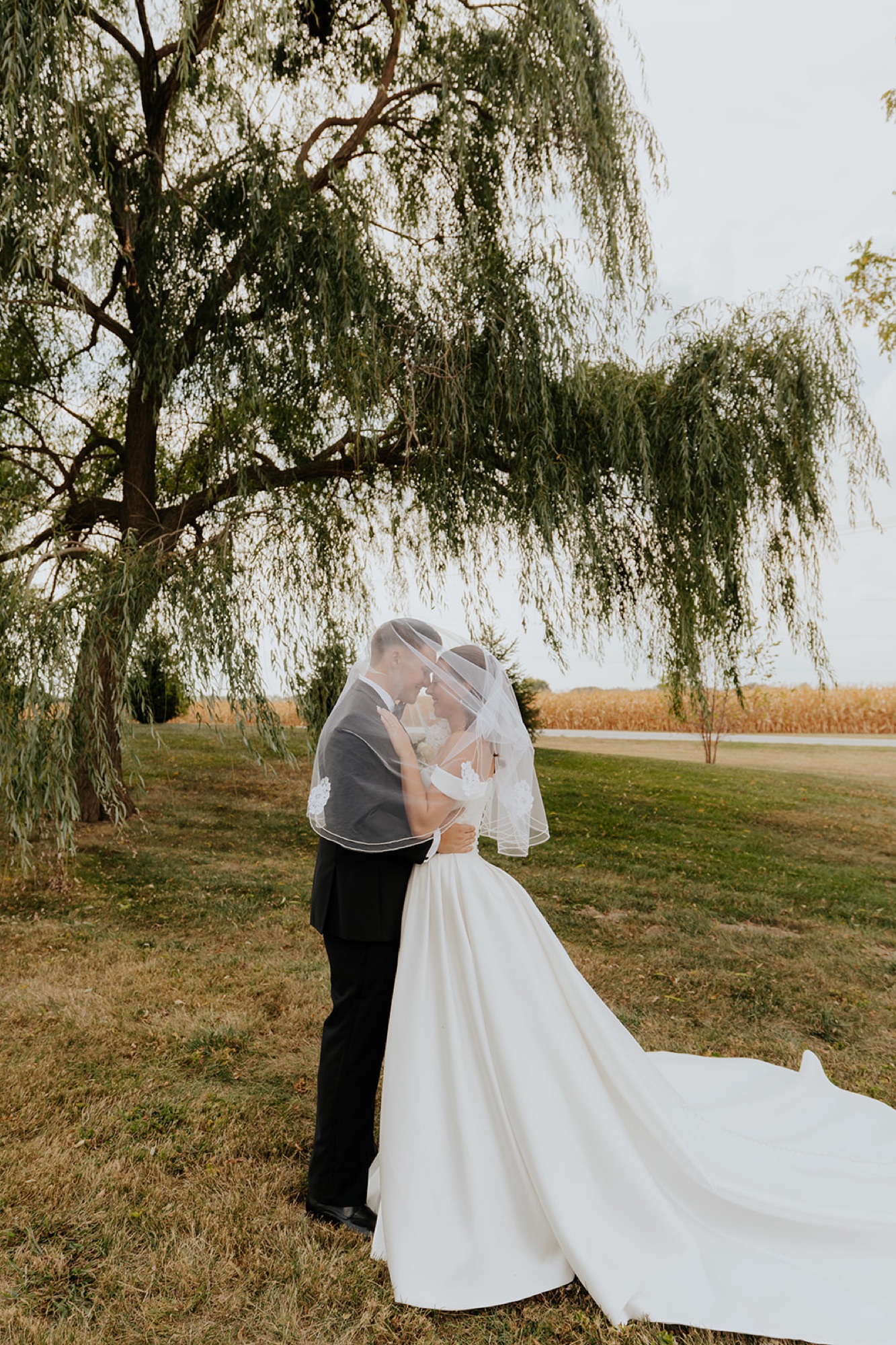 Regan and Reyn share a kiss under her veil beneath a weeping willow