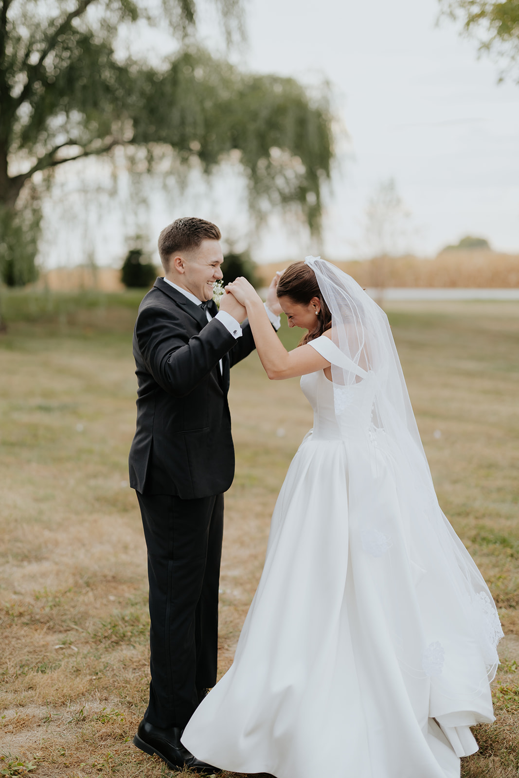 The groom kisses the bride's hand as she smiles beneath her veil
