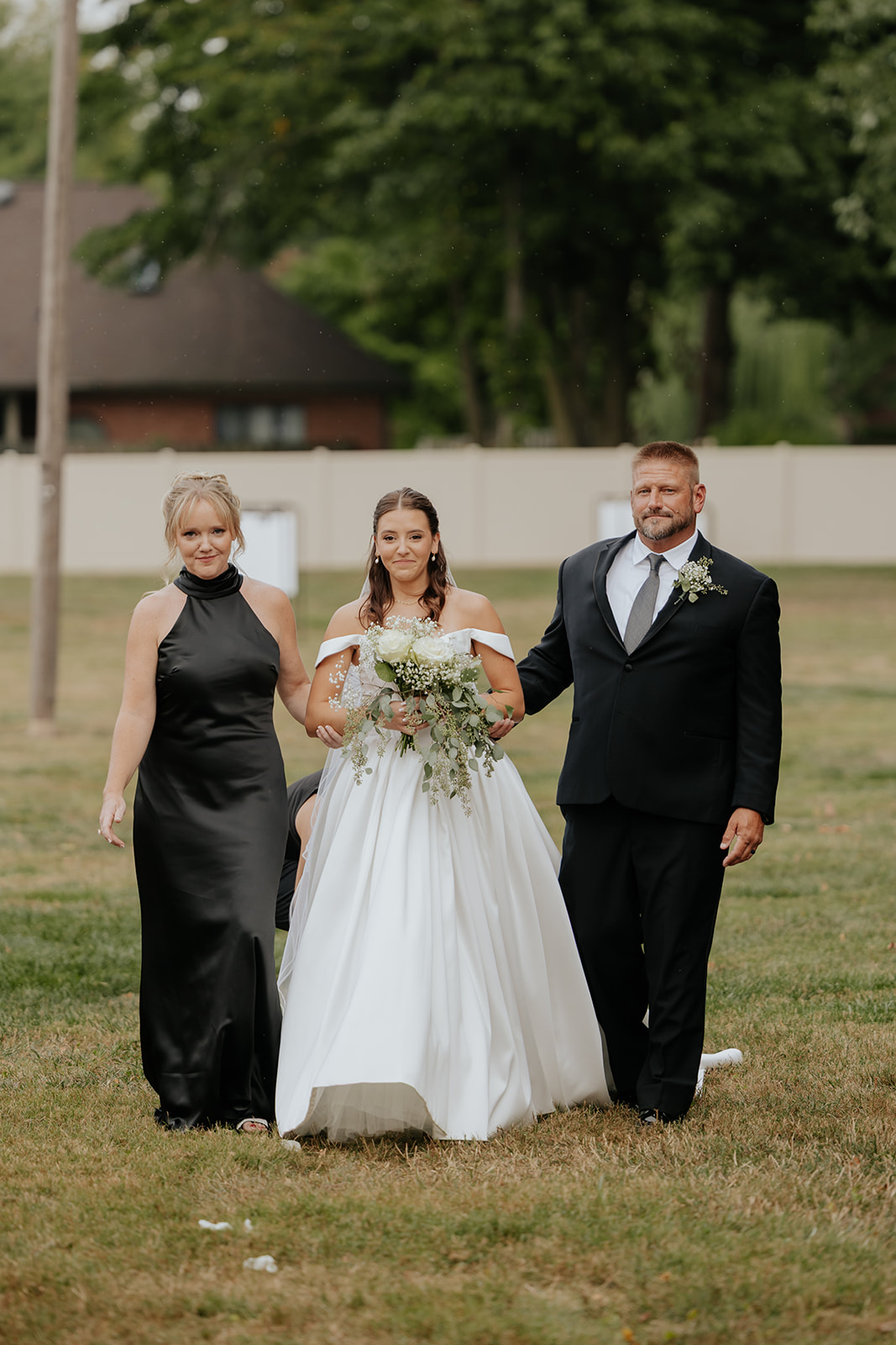 The bride walks down the aisle with her bouquet between two parents
