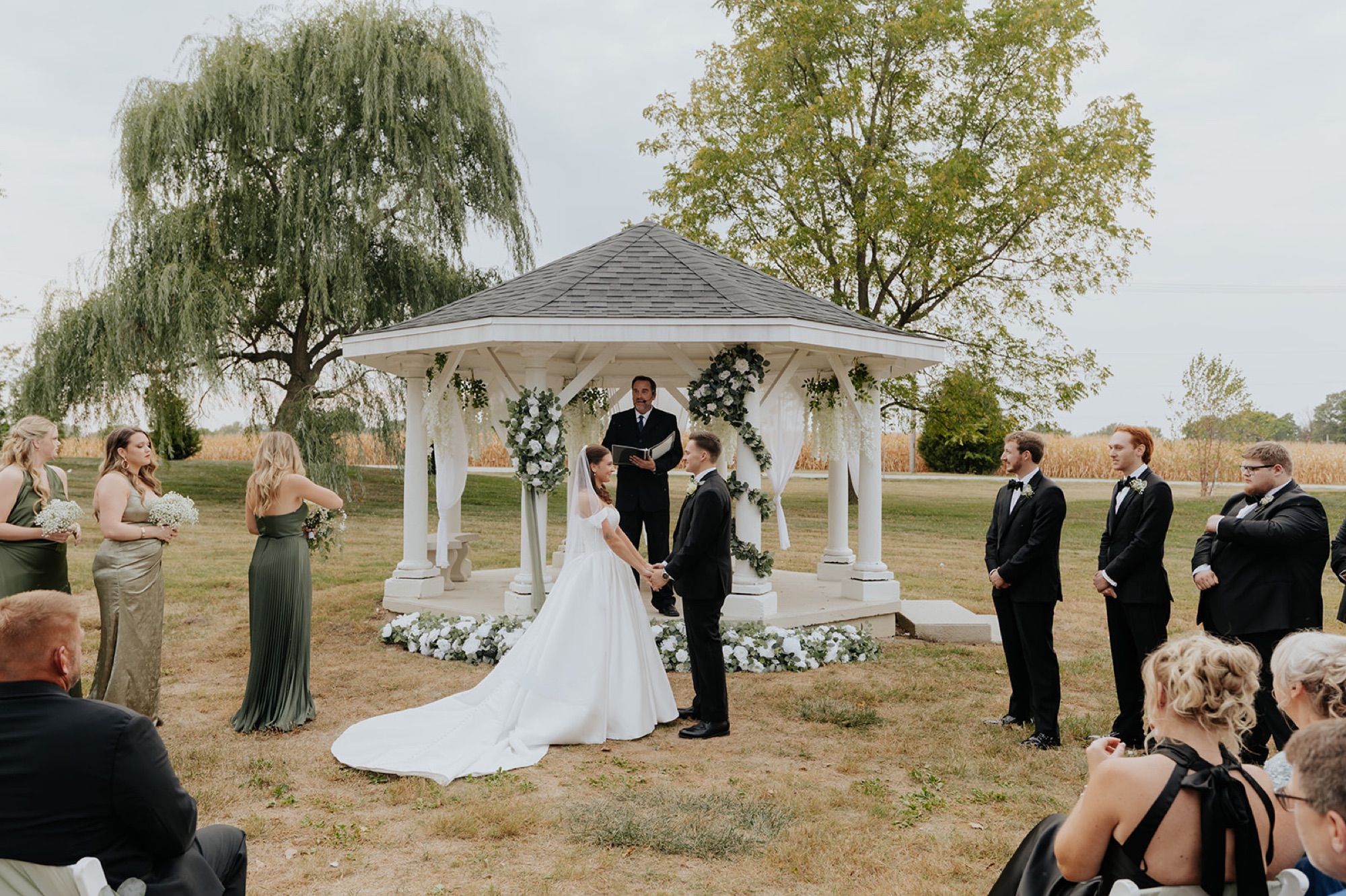 Regan and Reyn stand at the flower-covered gazebo during their ceremony at The Venue at Brookstone