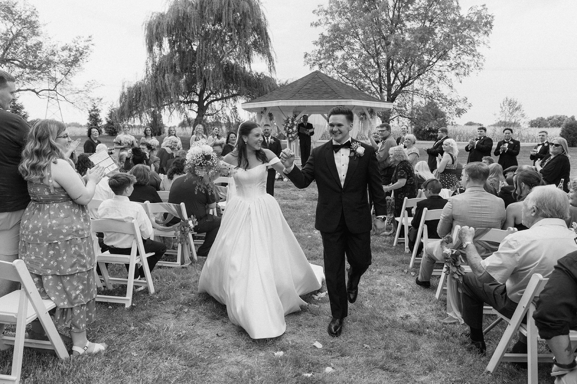 Black and white of Regan and Reyn walking back up the aisle as guests cheer